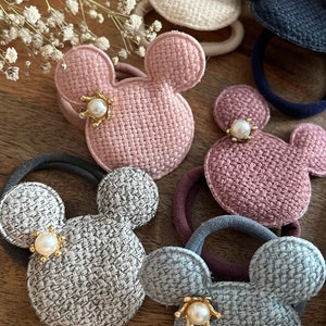 Könnte beinhalten: Fünf Haargummis mit Mickey-Maus-Motiv. Jedes Haargummi ist aus gewebtem Stoff gefertigt und hat einen Perlen- und Goldakzent.