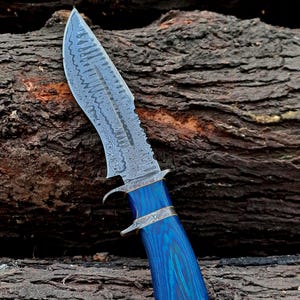 May include: A blue and silver Damascus steel hunting knife with a blue wood handle.