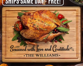 May include: A brown wooden cutting board with a roasted turkey, cranberries, and greenery on top. The board is engraved with the text "Seasoned with Love and Gratitude" and "THE WILLIAMS."