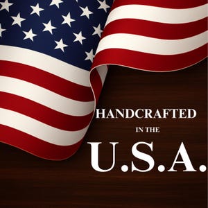 Może przedstawiać: Powiewająca amerykańska flaga z czerwonymi, białymi i niebieskimi pasami oraz białymi gwiazdami na niebieskim tle. Napis HANDCRAFTED IN THE U.S.A. jest wydrukowany białymi wielkimi literami na ciemnobrązowym tle z usłojeniem drewna pod flagą.