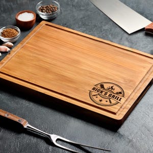 A wooden cutting board with a logo, knife, and various cooking utensils on a dark surface.