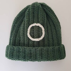 May include: A green knitted beanie with a white circle design.