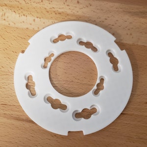 May include: White plastic ring with eight cloud-shaped cutouts. The ring is about 4 inches in diameter.