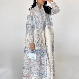 May include: A long, white, and blue patterned coat with a shawl collar. The coat has a map-like design with a light blue handbag.