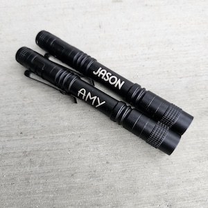 May include: Two black metal pens with the names "AMY" and "JASON" engraved on them.