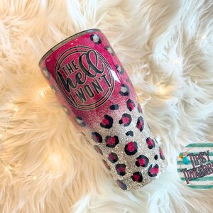 May include: A pink and silver glitter tumbler with a leopard print design. The tumbler has a black circle with the text "The hell I won't" in white.