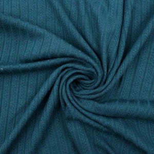 May include: Close-up of teal fabric with a ribbed texture. The fabric is swirled, creating a spiral pattern in the centre. The colour is a deep, muted teal, and the texture appears soft and slightly stretchy.