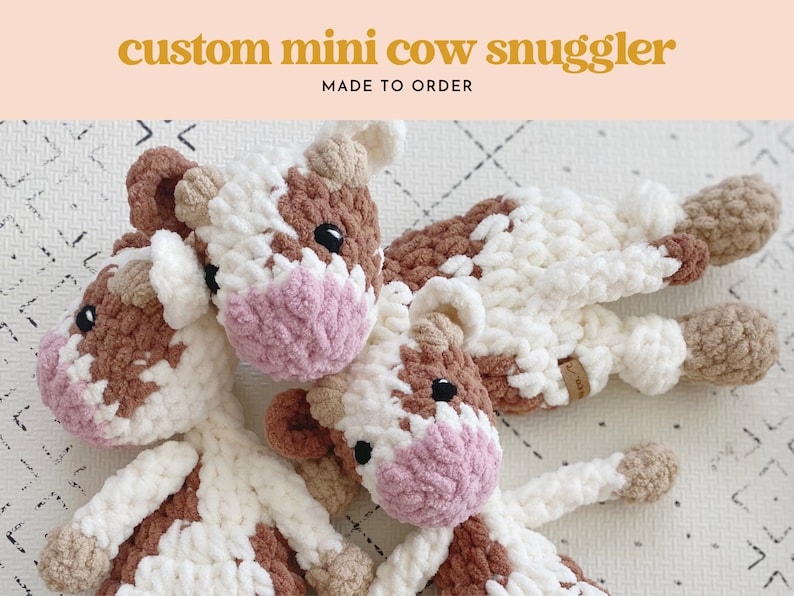 Pode incluir: Tr&ecirc;s peluches de vaca de croch&ecirc; em marrom, branco e rosa. Os peluches t&ecirc;m um padr&atilde;o de manchas e s&atilde;o feitos com um fio macio e felpudo. Os peluches est&atilde;o dispostos em um fundo branco com um padr&atilde;o de diamantes.