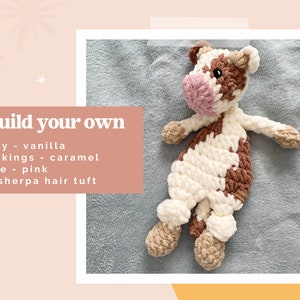 Pode incluir: Um brinquedo de pel&uacute;cia de vaca de croch&ecirc; com um corpo de baunilha, marcas de caramelo e um nariz rosa. O brinquedo est&aacute; deitado em uma superf&iacute;cie cinza e felpuda. O texto "build your own" est&aacute; escrito em negrito acima do brinquedo, seguido de uma lista de detalhes: "body - vanilla", "markings - caramel", "nose - pink", "no sherpa hair tuft".