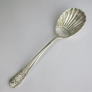 May include: A silver sugar spoon with an ornate design and a pierced bowl.