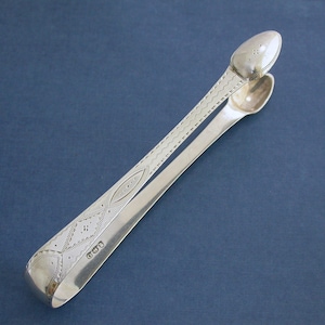 May include: Silver sugar tongs with an ornate design and a hallmarked date of "1900".