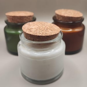 Può includere: Tre barattoli di vetro con tappi di sughero. I barattoli sono riempiti con una sostanza bianca. I barattoli sono su una superficie marrone chiaro.