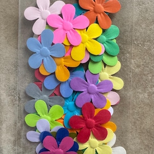 May include: A bag of colorful paper flowers, each with six petals and a raised center. The flowers are in various shades of pink, blue, green, yellow, orange, and red.