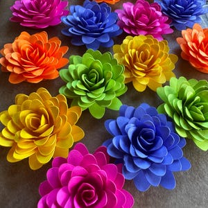 May include: A collection of 14 paper flowers in various colors, including pink, blue, green, yellow, and orange. The flowers are all made of paper and have a layered, ruffled appearance.
