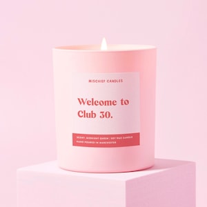 Peut inclure: Bougie en cire de soja rose avec le texte "Welcome to Club 30." et le parfum "Midnight Queen". La bougie est coul&eacute;e &agrave; la main &agrave; Manchester.