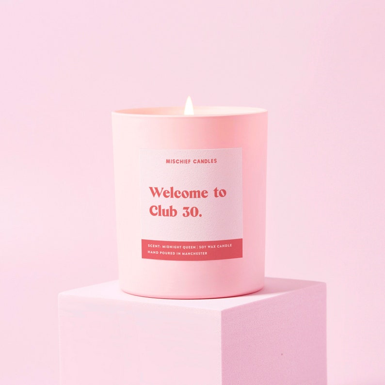 Peut inclure: Bougie en cire de soja rose avec le texte "Welcome to Club 30." et le parfum "Midnight Queen". La bougie est coul&eacute;e &agrave; la main &agrave; Manchester.