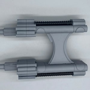 May include: A gray plastic model of a spaceship with two long, cylindrical engines and a central body with a Y-shaped structure.