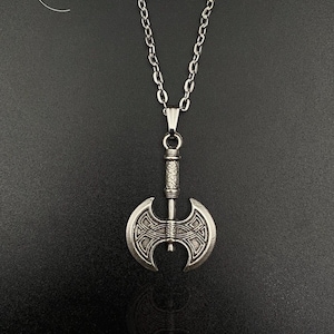 May include: A silver double-headed axe pendant on a silver chain necklace. The axe has a detailed design and is a popular symbol of strength and power.