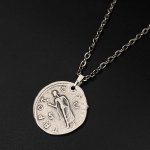 May include: Silver necklace with a round pendant featuring a Roman coin design. The pendant has an inscription that reads "SPQR" and depicts a figure standing with a staff.