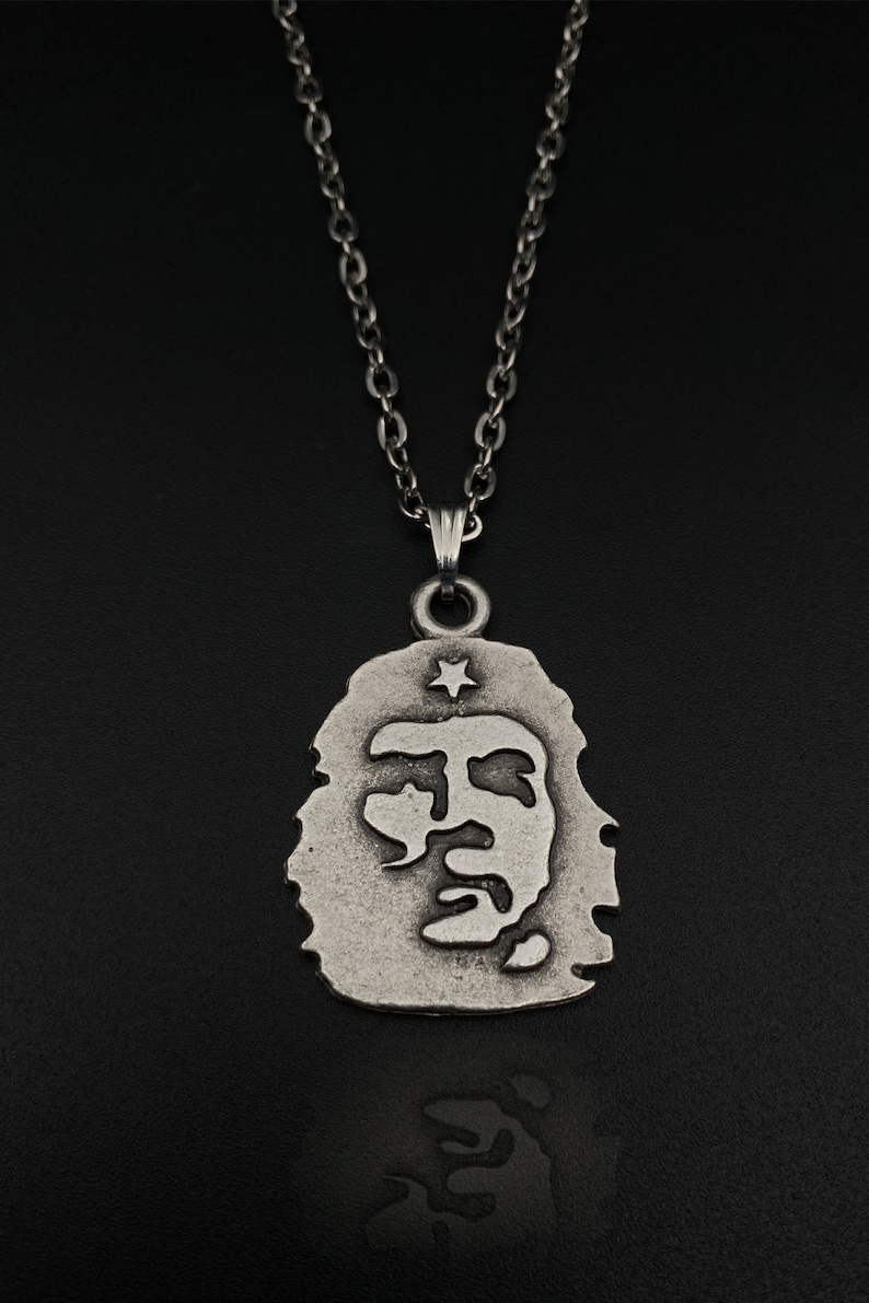 K&ouml;nnte beinhalten: Eine silberne Kettenkette mit einem Anh&auml;nger, der ein Profil von Che Guevara mit einem Stern &uuml;ber seinem Kopf zeigt.