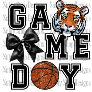 May include: Black and white graphic design with the words "GAME DAY" in a varsity style font. The design also includes a black bow, a tiger head, and a basketball with orange glitter.