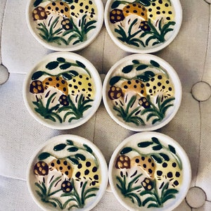 May include: Set of six ceramic coasters featuring a hand-painted design of mushrooms with brown and yellow spots on a green background.