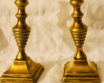 May include: A pair of antique brass candlesticks with a fluted design. The candlesticks have a square base and a round top.