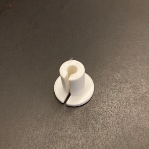 May include: White plastic 3D printed ring holder with a split base.