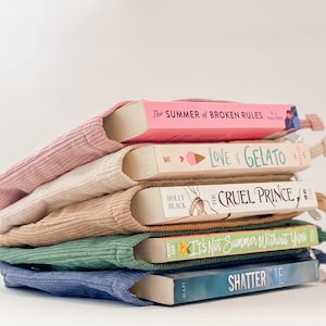Pode incluir: Uma pilha de cinco livros, cada um em uma capa de livro de veludo cotel&ecirc;. Os livros t&ecirc;m t&iacute;tulos como "The Summer of Broken Rules" e "Love & Gelato". As capas s&atilde;o em tons de rosa, bege, castanho claro, verde e azul.
