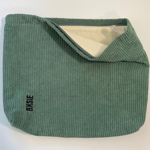 Pode incluir: Uma bolsa de veludo cotel&ecirc; verde s&aacute;lvia com fecho de correr. A bolsa tem formato retangular e aspecto macio e texturizado. A palavra "Bksie" est&aacute; impressa em preto no canto inferior esquerdo. O interior &eacute; bege claro.