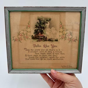 May include: A framed print with a poem titled "Folks Like You" by Edgar A. Guest. The poem is about the importance of good people in life. The print features a watercolor illustration of a small cottage in a forest setting.