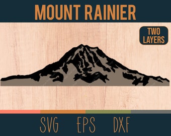 Op de afbeelding: Een zwart silhouet van Mount Rainier, een berg met een besneeuwde top, tegen een bruine houten achtergrond. De tekst "MOUNT RAINIER" staat boven de berg en "TWO LAYERS" staat in een wit rechthoek in de rechterbovenhoek.
