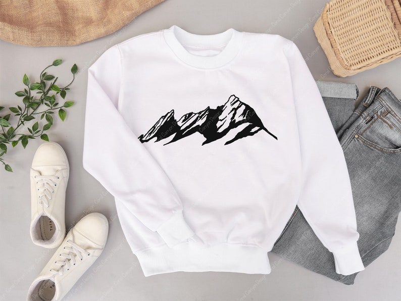Pu&ograve; includere: Felpa bianca con una stampa grafica di una catena montuosa nera. La felpa ha maniche lunghe e un collo rotondo.