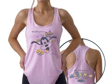May include: A light purple racerback tank top featuring a graphic of Goofy with the text Walt Disney World Goofy's Challenge 2027 39.3 Miles. The back of the tank top displays the text Walt Disney World Marathon Weekend 2027 in a circular inset.