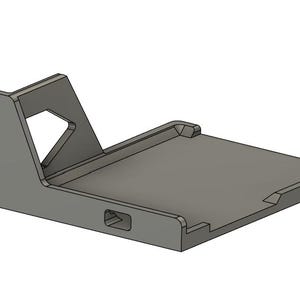 May include: A gray, L-shaped metal mounting bracket featuring a flat, rectangular base with raised edges and a vertical support arm. The vertical section includes two elongated oval mounting slots and a triangular cutout for structural reinforcement.