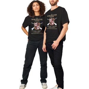May include: Two people wearing black t-shirts with a graphic design of a tavern logo. The logo features a shield with a cross and the text "The Winchester Tavern" and "Craft Ales - Fine Wines - Hungry Zombies".