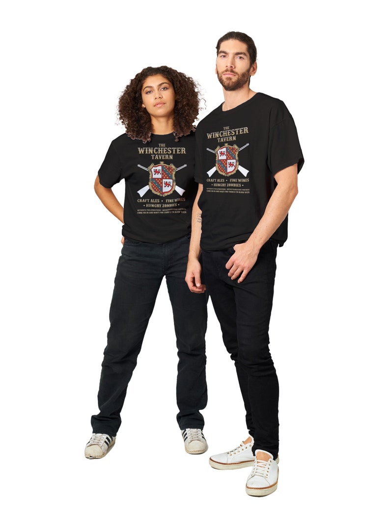 May include: Two people wearing black t-shirts with a graphic design of a tavern logo. The logo features a shield with a cross and the text "The Winchester Tavern" and "Craft Ales - Fine Wines - Hungry Zombies".