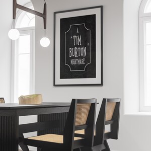 K&ouml;nnte beinhalten: Ein gerahmter Schwarz-Wei&szlig;-Druck mit dem Text "A Tim Burton Nightmare" h&auml;ngt an einer wei&szlig;en Wand. Darunter sind ein schwarzer Esstisch und St&uuml;hle mit gewebten R&uuml;cken zu sehen. &Uuml;ber dem Tisch h&auml;ngt eine moderne Leuchte mit zwei kugelf&ouml;rmigen Gl&uuml;hbirnen.