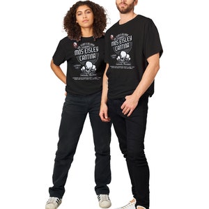 May include: Two people wearing black t-shirts and black jeans stand side by side. The t-shirts feature the text "Mos Eisley Cantina" with a graphic design. The woman wears white sneakers, and the man wears white sneakers.