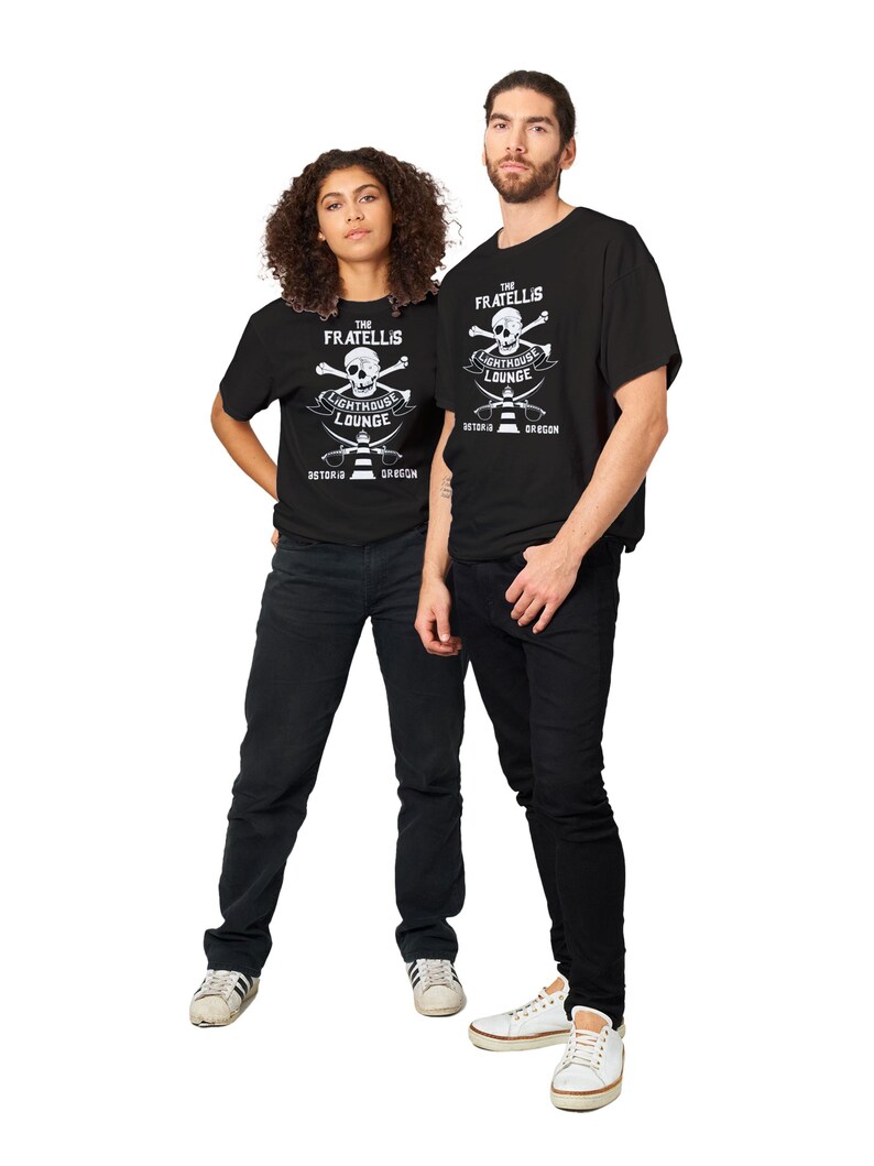 May include: Two people wearing black t-shirts with a white skull and crossbones graphic. The graphic says "The Fratellis Lighthouse Lounge Astoria Oregon".
