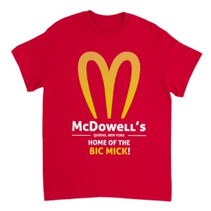May include: Red t-shirt with a yellow heart-shaped logo and the text "McDowell's" above "Queens, New York" and "HOME OF THE BIC MICK!" in white. The shirt is a short-sleeved crew neck.