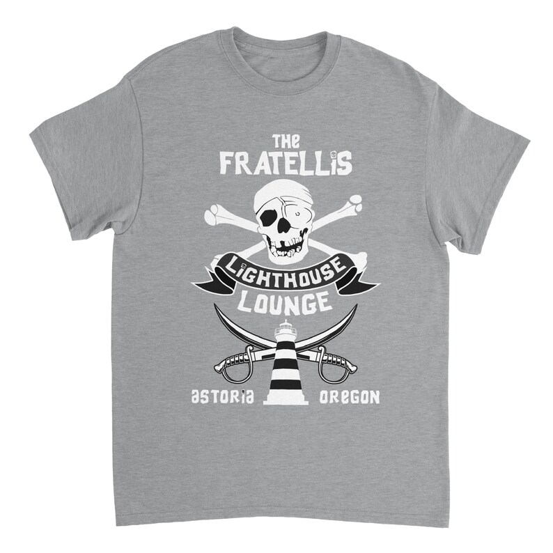 May include: A gray t-shirt with a white graphic design featuring a skull and crossbones, a lighthouse, and the text "The Fratellis Lighthouse Lounge Astoria Oregon".