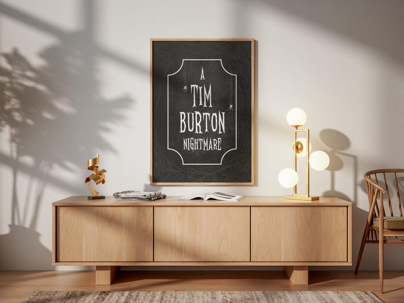 K&ouml;nnte beinhalten: Ein gerahmtes Poster mit dem Text "A Tim Burton Nightmare" in Wei&szlig; auf schwarzem Hintergrund. Das Poster h&auml;ngt &uuml;ber einem hellen Holzschrank. Eine goldene Lampe mit kugelf&ouml;rmigen Gl&uuml;hbirnen und eine kleine Skulptur befinden sich auf dem Schrank.