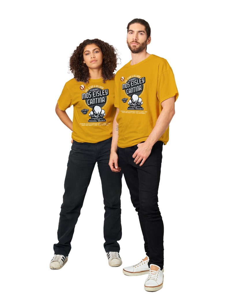 May include: Mustard yellow t-shirts with the text "Mos Eisley Cantina" and a graphic of three skulls. The shirts are worn with black jeans and white sneakers. The image features a man and a woman.