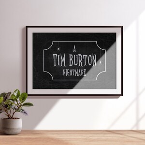 K&ouml;nnte beinhalten: Gerahmter Kunstdruck mit dem Text "A Tim Burton Nightmare" in wei&szlig;er, Vintage-Schrift auf schwarzem Hintergrund. Der Druck befindet sich in einem schwarzen Rahmen und h&auml;ngt an einer wei&szlig;en Wand. Eine kleine Topfpflanze steht auf einer Holzoberfl&auml;che.