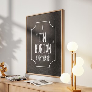 K&ouml;nnte beinhalten: Ein gerahmter Schwarz-Wei&szlig;-Druck mit dem Text "A Tim Burton Nightmare" in einer dekorativen Schriftart. Der Druck befindet sich in einem hellen Holzrahmen und h&auml;ngt an einer wei&szlig;en Wand. Rechts befindet sich eine moderne Lampe mit vier kugelf&ouml;rmigen Lichtern.