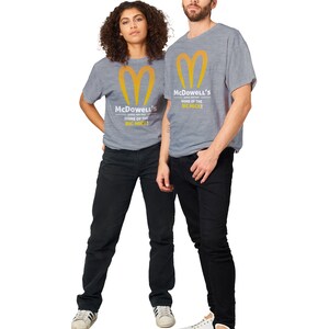 May include: Two people wearing gray t-shirts with the McDowell's logo and text. The logo is a stylized yellow heart shape. The text reads "McDowell's HOME OF THE BIC MICK!". They are wearing black pants and white sneakers.