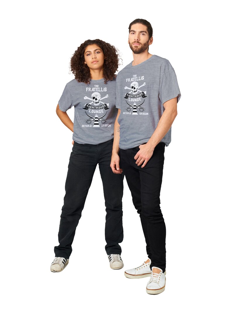 May include: Two people wearing grey t-shirts with a white skull and crossbones graphic. The graphic says "The Fratellis Lighthouse Lounge Astoria Oregon".