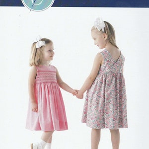 May include: Two girls wearing pink and floral dresses, holding hands. The girls are wearing white shoes and headbands. The image is from a children's clothing pattern company called "Children's Corner Patterns".