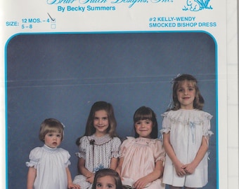 May include: Five young girls wearing smocked bishop dresses in various colors, including white, pink, blue, and a white dress with black polka dots. The girls are standing and sitting in front of a blue background. The image includes the text "Briar Patch Designs, Inc. By Becky Summers #2 Kelly-Wendy Smocked Bishop Dress".